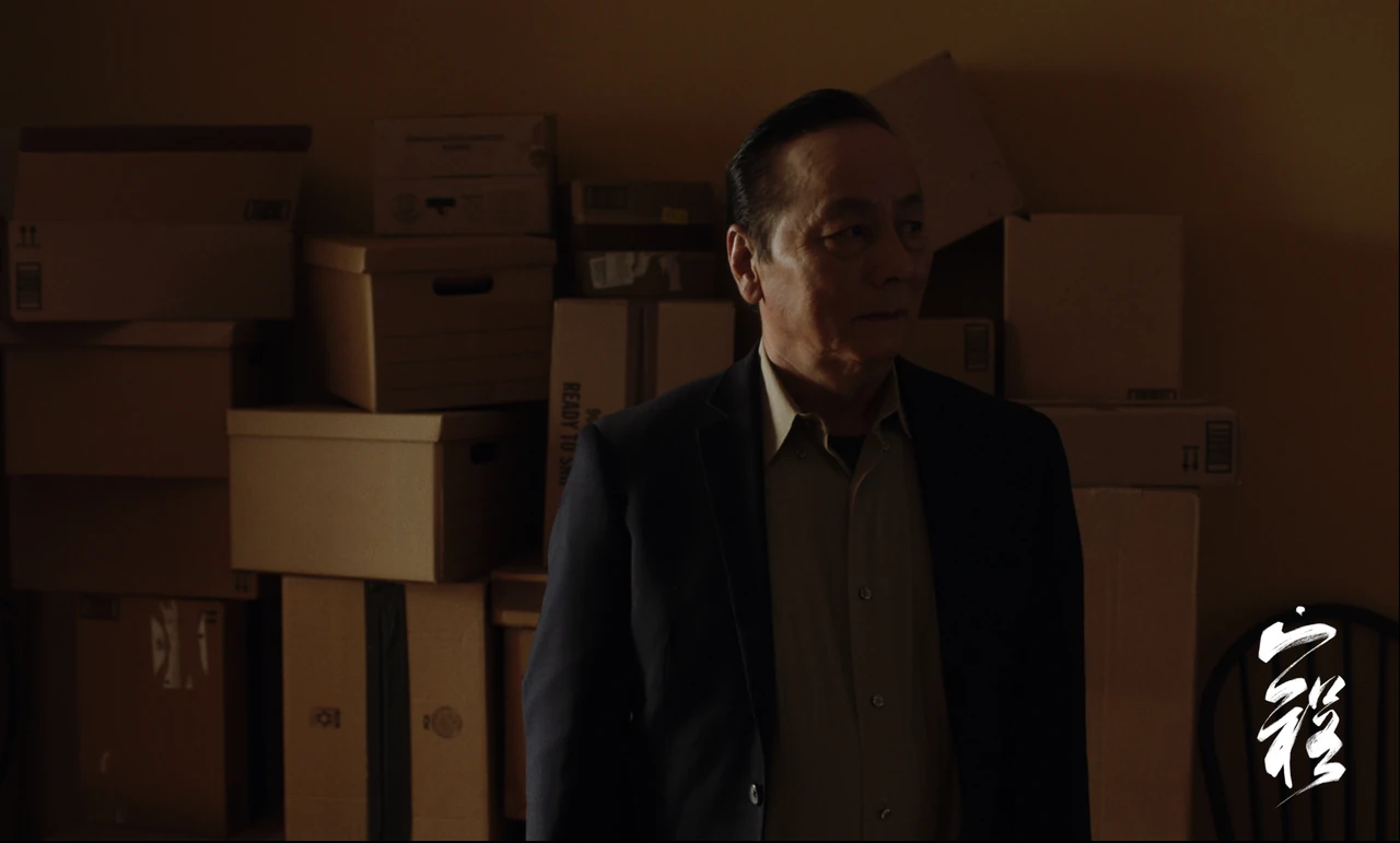 A man stands in a dim room filled with cardboard boxes.